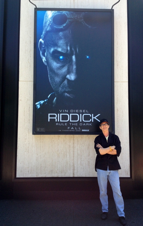 David Twohy on Universal Lot with giant poster of his movie, August 2013